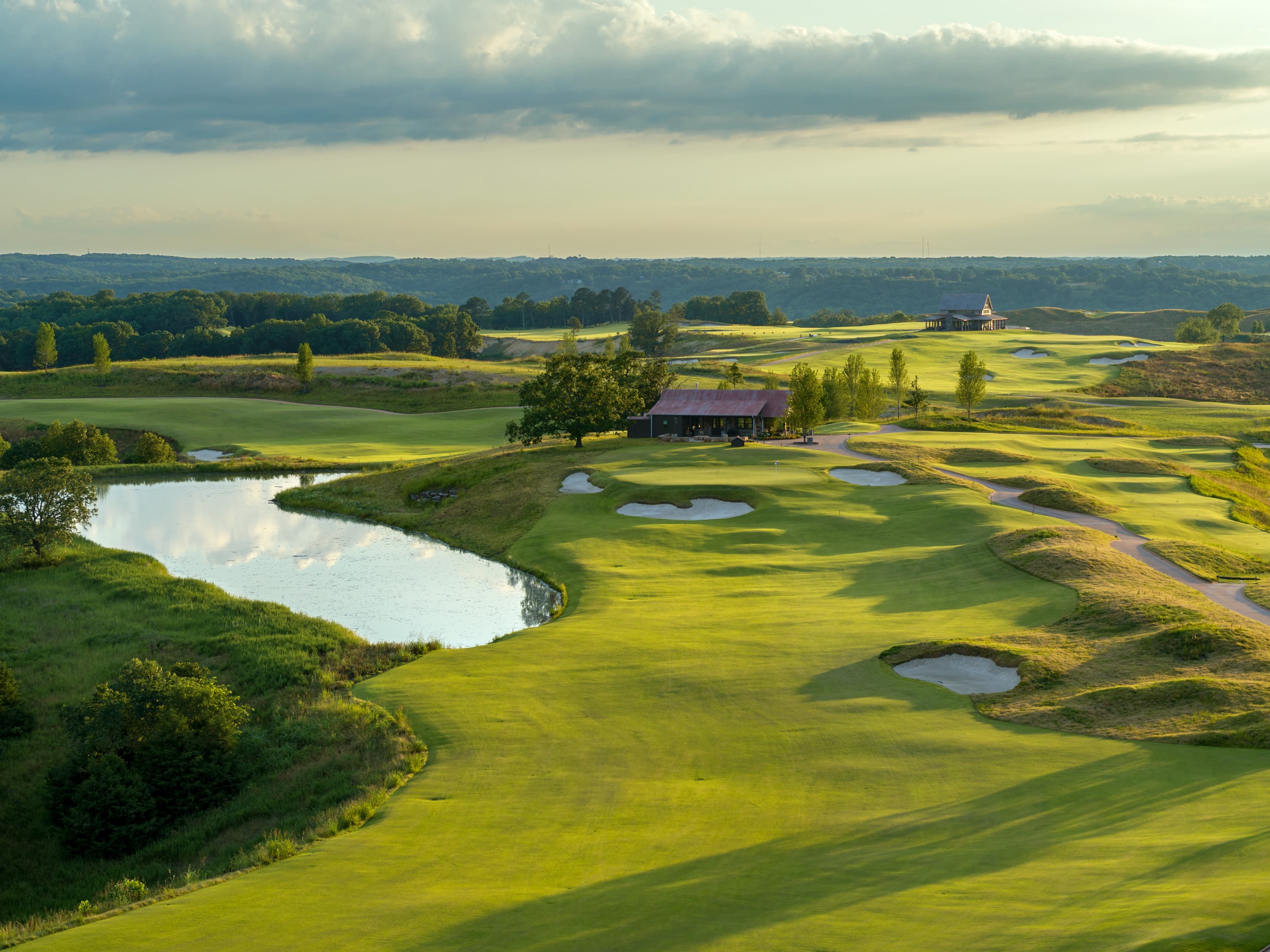 Aerial view of Ozarks National Golf Course with pond, fairway, and clubhouse in the distance