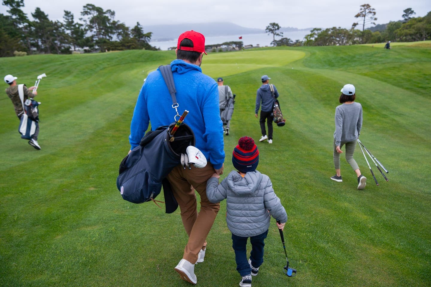 A family of golfers walking the fairway at The Hay Short Course with a child carrying a junior club