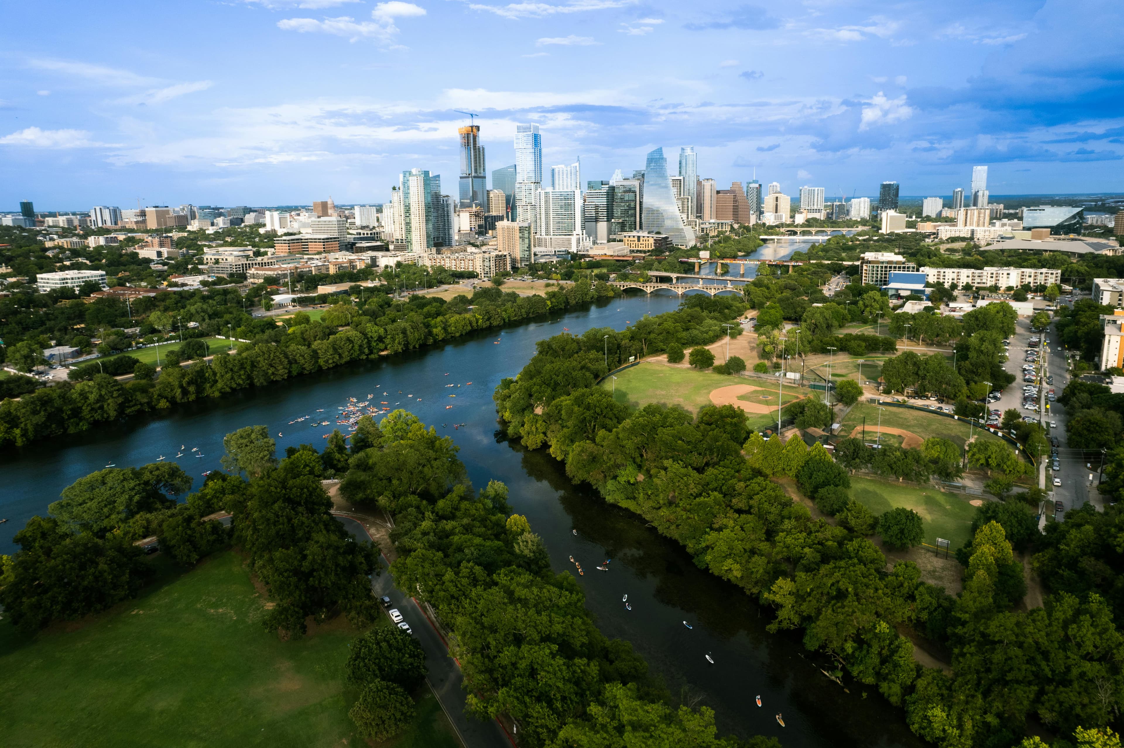 Aerial view of downtown Austin skyline and Lady Bird Lake lined with trees